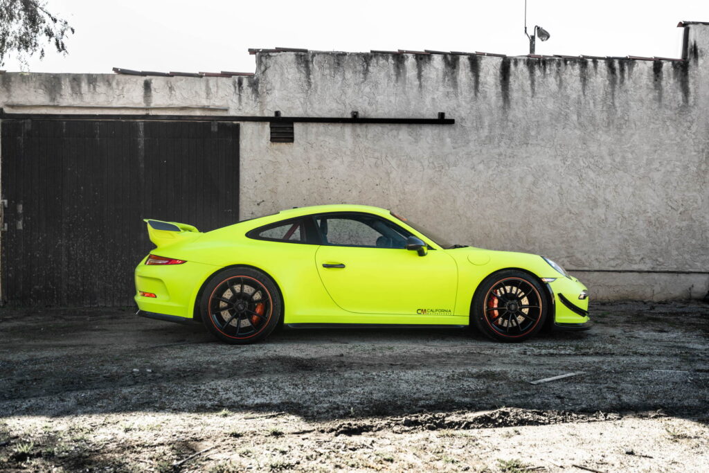 Porsche 911 GT3 in a gloss lime yellow color-change wrap with black stripes by California Motorsports