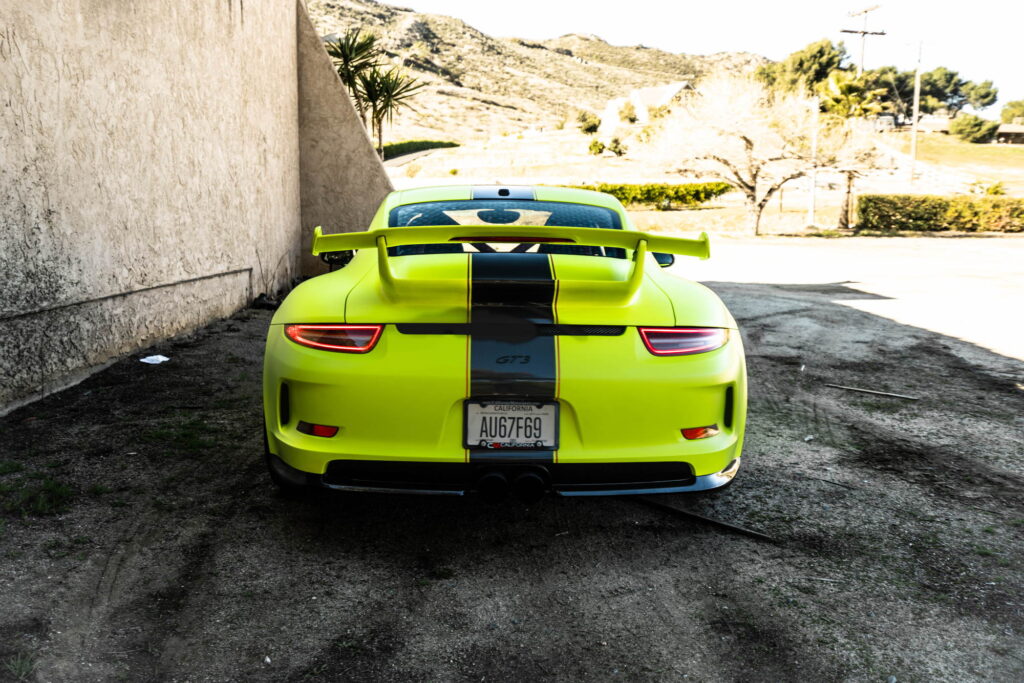 Porsche 911 GT3 in a gloss lime yellow color-change wrap with black stripes by California Motorsports