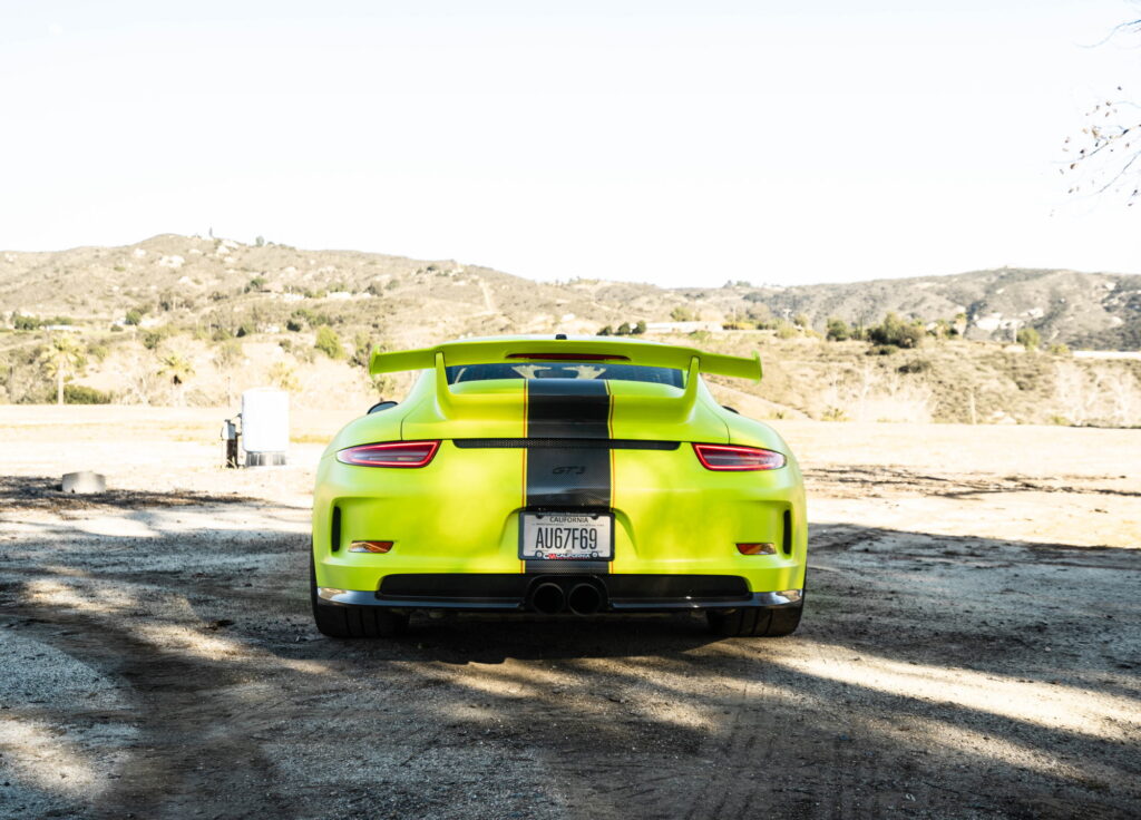 Porsche 911 GT3 in a gloss lime yellow color-change wrap with black stripes by California Motorsports